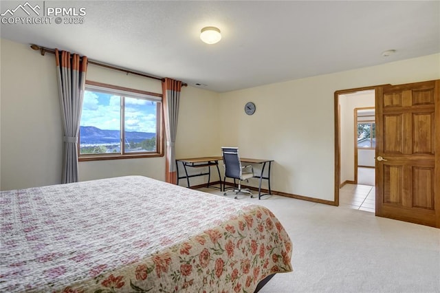 bedroom with multiple windows, light carpet, and baseboards