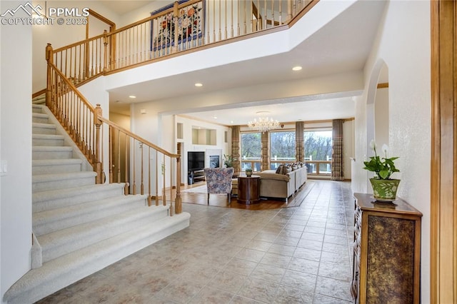 foyer entrance with stairs, a towering ceiling, a chandelier, and recessed lighting
