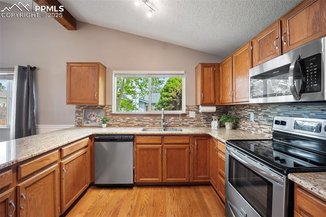 6277 Gunshot Pass Dr, Colorado Springs, CO 80917 - kitchen featuring appliances with stainless steel finishes, a sink, light wood-type flooring, brown cabinetry, and a textured ceiling