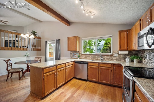 6277 Gunshot Pass Dr, Colorado Springs, CO 80917 - kitchen featuring a sink, appliances with stainless steel finishes, a peninsula, brown cabinets, and decorative backsplash