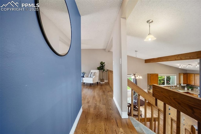 6277 Gunshot Pass Dr, Colorado Springs, CO 80917 - hall with wood finished floors, baseboards, beamed ceiling, a textured ceiling, and a chandelier