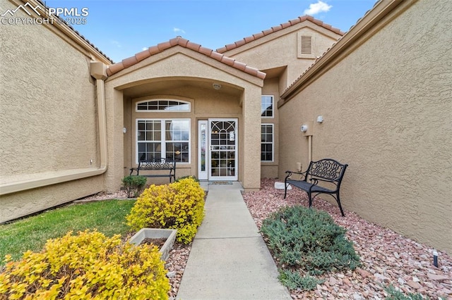 entrance to property featuring stucco siding and a tiled roof