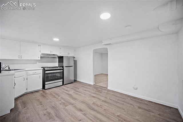137 N 14th St, Colorado Springs, CO 80904 - kitchen with under cabinet range hood, white cabinets, a sink, light wood finished floors, and stainless steel appliances