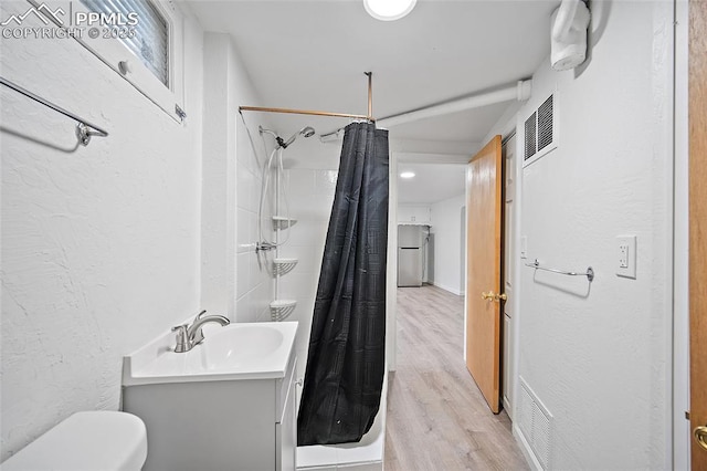 137 N 14th St, Colorado Springs, CO 80904 - full bath with a textured wall, vanity, toilet, a shower with shower curtain, and wood finished floors