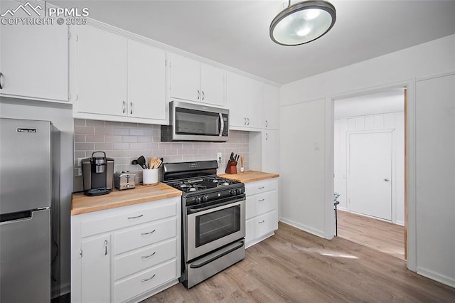 137 N 14th St, Colorado Springs, CO 80904 - kitchen featuring baseboards, white cabinets, tasteful backsplash, light wood finished floors, and appliances with stainless steel finishes