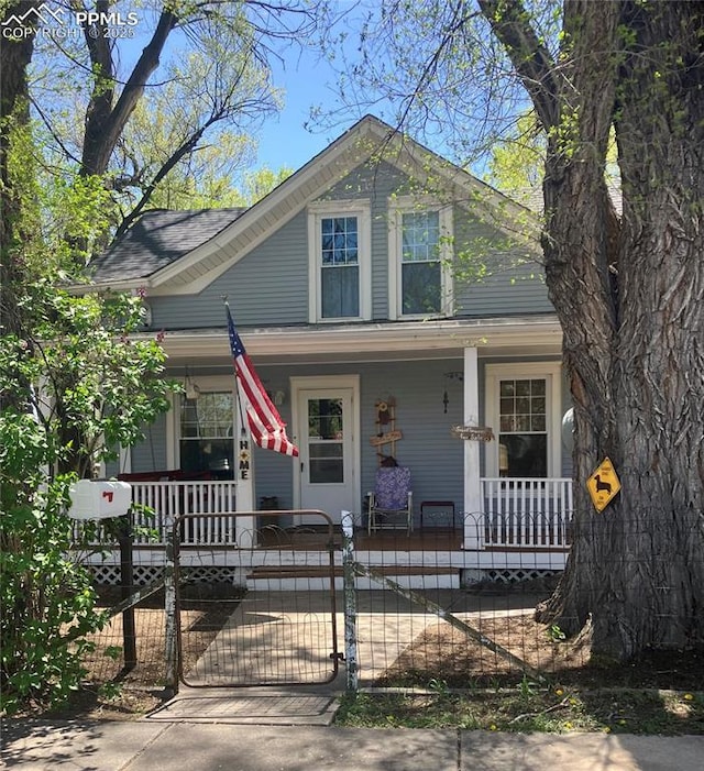 bungalow featuring covered porch, a gate, and a fenced front yard