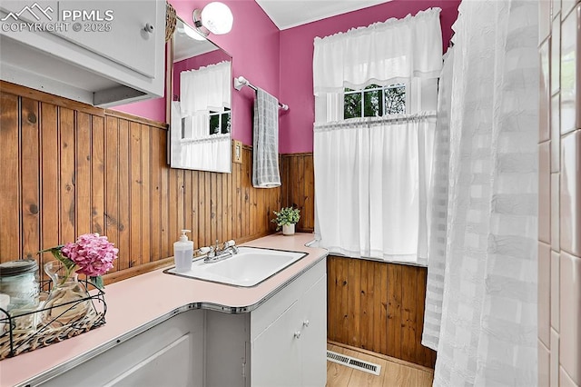 bathroom featuring wainscoting, visible vents, wood walls, vanity, and wood finished floors