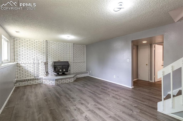 1950 Rusty Hinge Dr, Colorado Springs, CO 80920 - unfurnished living room featuring a textured ceiling, a wood stove, wood finished floors, and baseboards