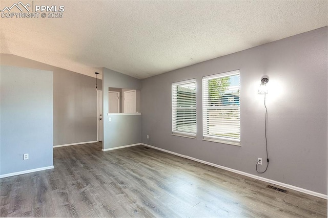 1950 Rusty Hinge Dr, Colorado Springs, CO 80920 - empty room featuring a textured ceiling, wood finished floors, vaulted ceiling, and baseboards