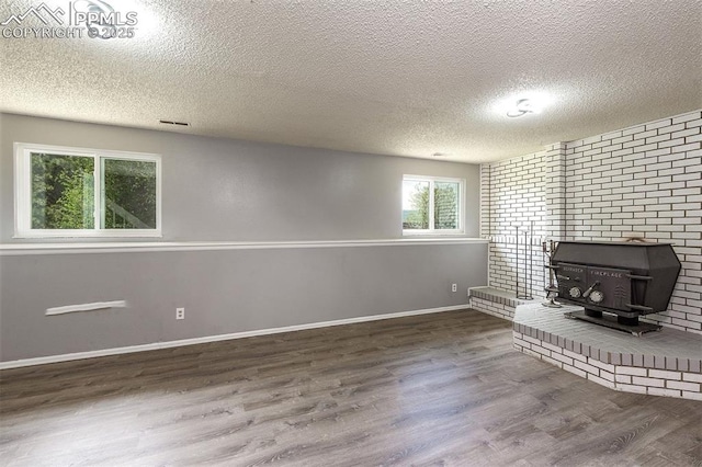 1950 Rusty Hinge Dr, Colorado Springs, CO 80920 - unfurnished living room featuring a wood stove, a textured ceiling, wood finished floors, and baseboards
