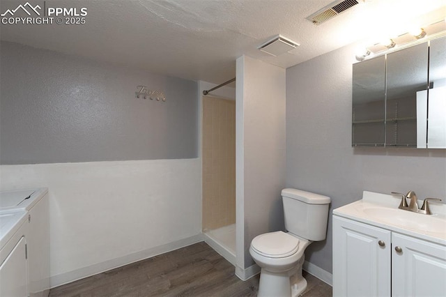 1950 Rusty Hinge Dr, Colorado Springs, CO 80920 - full bath with washing machine and clothes dryer, vanity, toilet, wood finished floors, and a textured ceiling