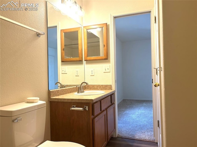 bathroom featuring vanity, a textured wall, and toilet