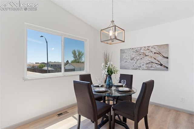 929 Bromefield Dr, Fountain, CO 80817 - dining space featuring visible vents, vaulted ceiling, wood finished floors, baseboards, and a notable chandelier