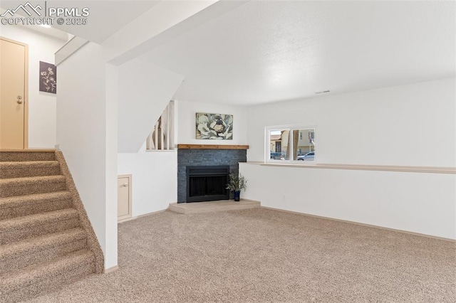 929 Bromefield Dr, Fountain, CO 80817 - unfurnished living room featuring carpet flooring, a fireplace with raised hearth, and stairs