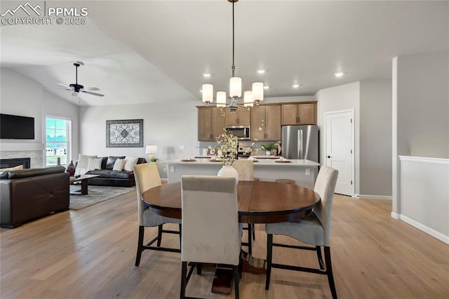 9484 Simper Hts, Colorado Springs, CO 80924 - dining area with light wood-style floors, ceiling fan, a chandelier, a fireplace, and baseboards