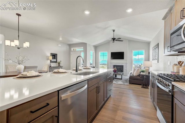 9484 Simper Hts, Colorado Springs, CO 80924 - kitchen featuring stainless steel appliances, a sink, ceiling fan, a glass covered fireplace, and light wood-style flooring