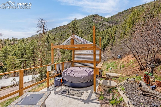 view of patio / terrace featuring a gazebo, a mountain view, and a forest view
