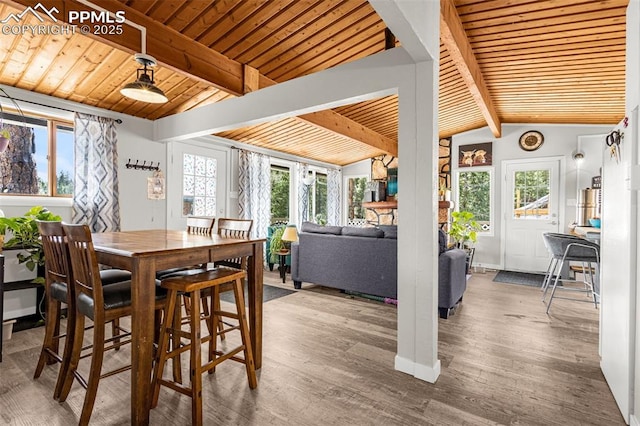dining space with vaulted ceiling with beams, wood finished floors, and wooden ceiling