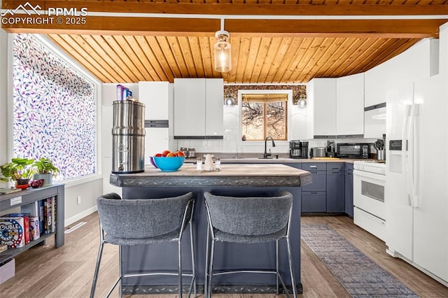 kitchen with white cabinets, white appliances, wood finished floors, beamed ceiling, and wood ceiling