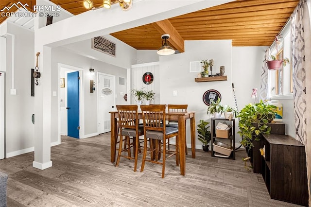 dining room featuring beam ceiling, baseboards, wood finished floors, visible vents, and wood ceiling
