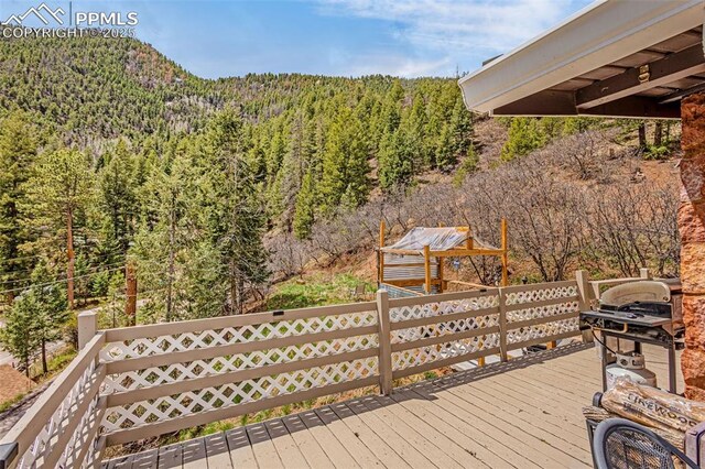 wooden terrace with a view of trees and a mountain view