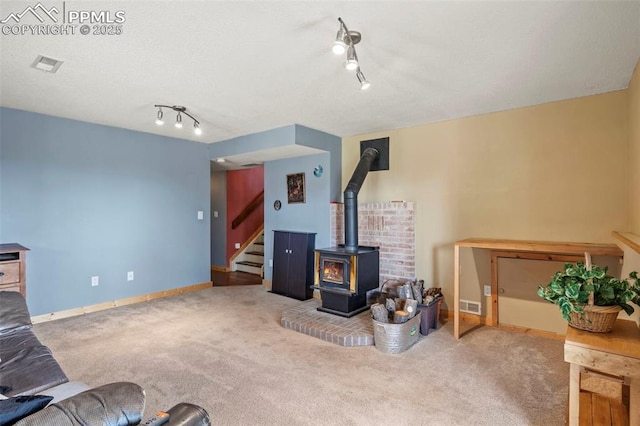 1200 Forest Edge Rd, Woodland Park, CO 80863 - living room featuring a wood stove, stairway, rail lighting, visible vents, and carpet floors