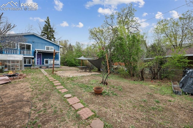 view of yard with fence, a fire pit, a deck, and a greenhouse