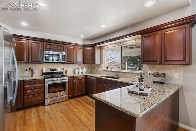 7820 Curlew Ct, Colorado Springs, CO 80920 - kitchen with light wood-type flooring, a sink, appliances with stainless steel finishes, and a peninsula