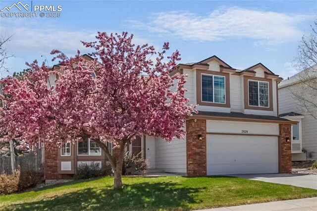 7820 Curlew Ct, Colorado Springs, CO 80920 - view of front of home featuring a garage, a front yard, driveway, and brick siding