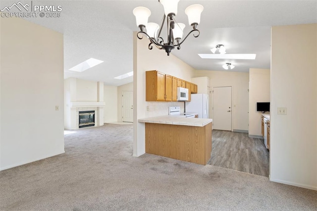 kitchen featuring a skylight, light colored carpet, white appliances, and open floor plan
