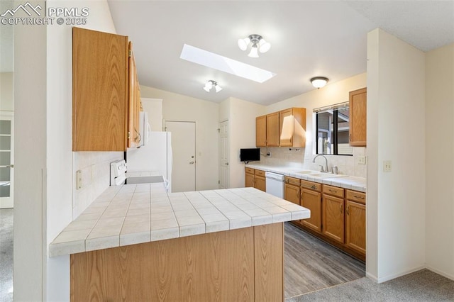 kitchen with decorative backsplash, a skylight, stove, a sink, and tile counters