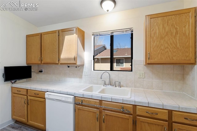 kitchen with white dishwasher, light countertops, tasteful backsplash, and a sink