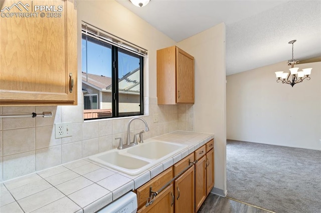 kitchen featuring tile counters, a sink, backsplash, and a chandelier