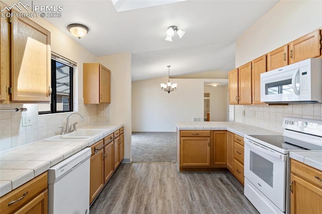 kitchen with an inviting chandelier, a sink, white appliances, tile countertops, and wood finished floors