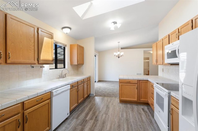 kitchen with a notable chandelier, a sink, white appliances, light wood-style flooring, and a peninsula