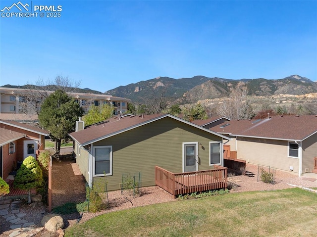 rear view of house with a lawn and a deck with mountain view