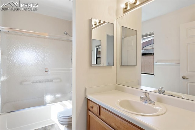 bathroom featuring toilet, bath / shower combo with glass door, and vanity