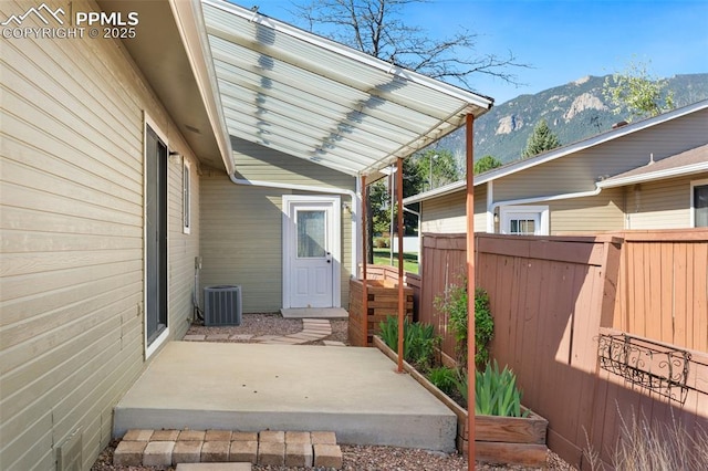 exterior space with central AC, fence, a mountain view, and a patio area