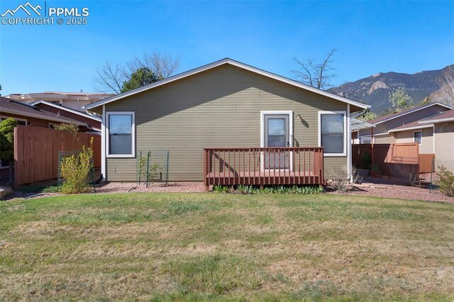 back of property with fence, a yard, and a deck with mountain view