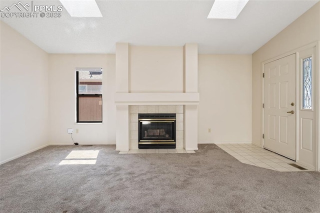 unfurnished living room with a skylight, baseboards, carpet flooring, and a tile fireplace