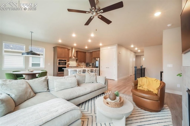 living area with a ceiling fan, baseboards, recessed lighting, and light wood-style floors