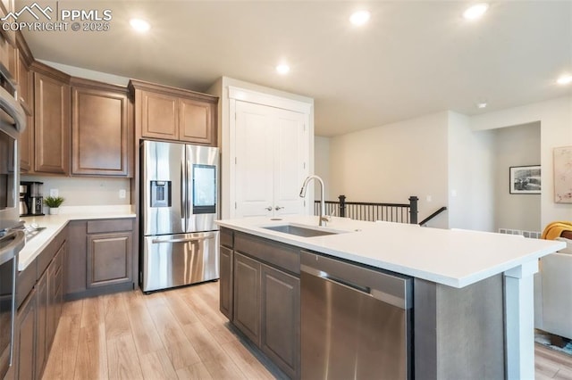 kitchen with a sink, light countertops, light wood-style flooring, stainless steel appliances, and recessed lighting