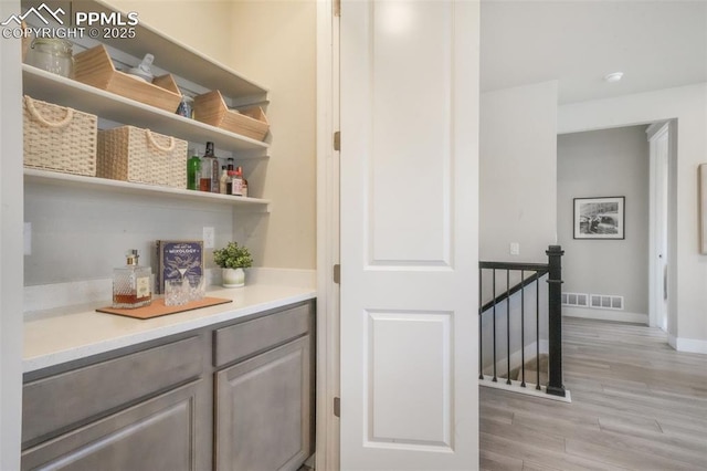 bar with visible vents, light wood finished floors, and baseboards