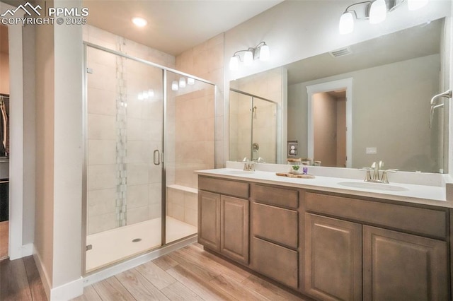 full bath featuring visible vents, a shower stall, a sink, and wood finished floors