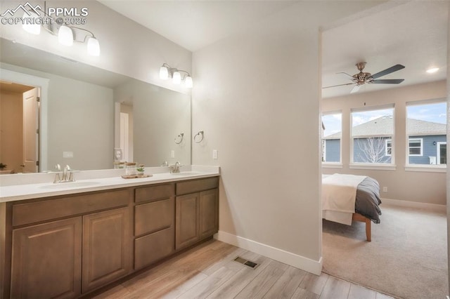 ensuite bathroom with a ceiling fan, baseboards, visible vents, and a sink