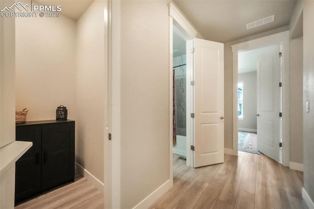 corridor with baseboards, visible vents, and light wood-style flooring