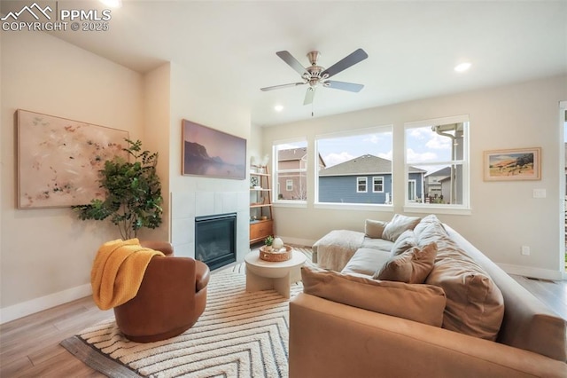 living room featuring wood finished floors, baseboards, recessed lighting, a tiled fireplace, and a ceiling fan