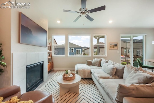 living area featuring ceiling fan, light wood-style floors, a tiled fireplace, recessed lighting, and baseboards