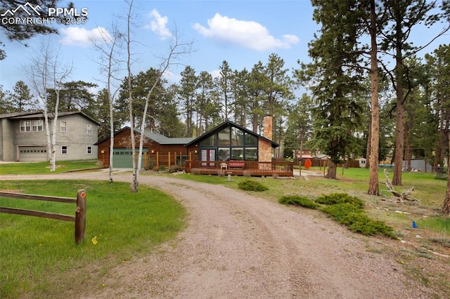 500 W Kellys Rd, Woodland Park, CO 80863 - view of front facade with curved driveway, a garage, a chimney, a deck, and a front yard