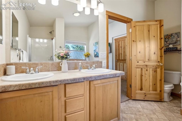 bathroom featuring double vanity, a sink, a shower, and toilet